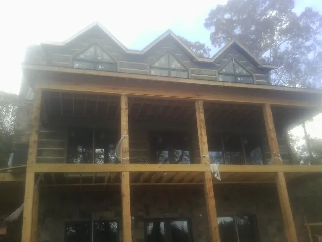 Dormers and porch framing on a large log home under construction — Roof Coating work by our crew in Windfall