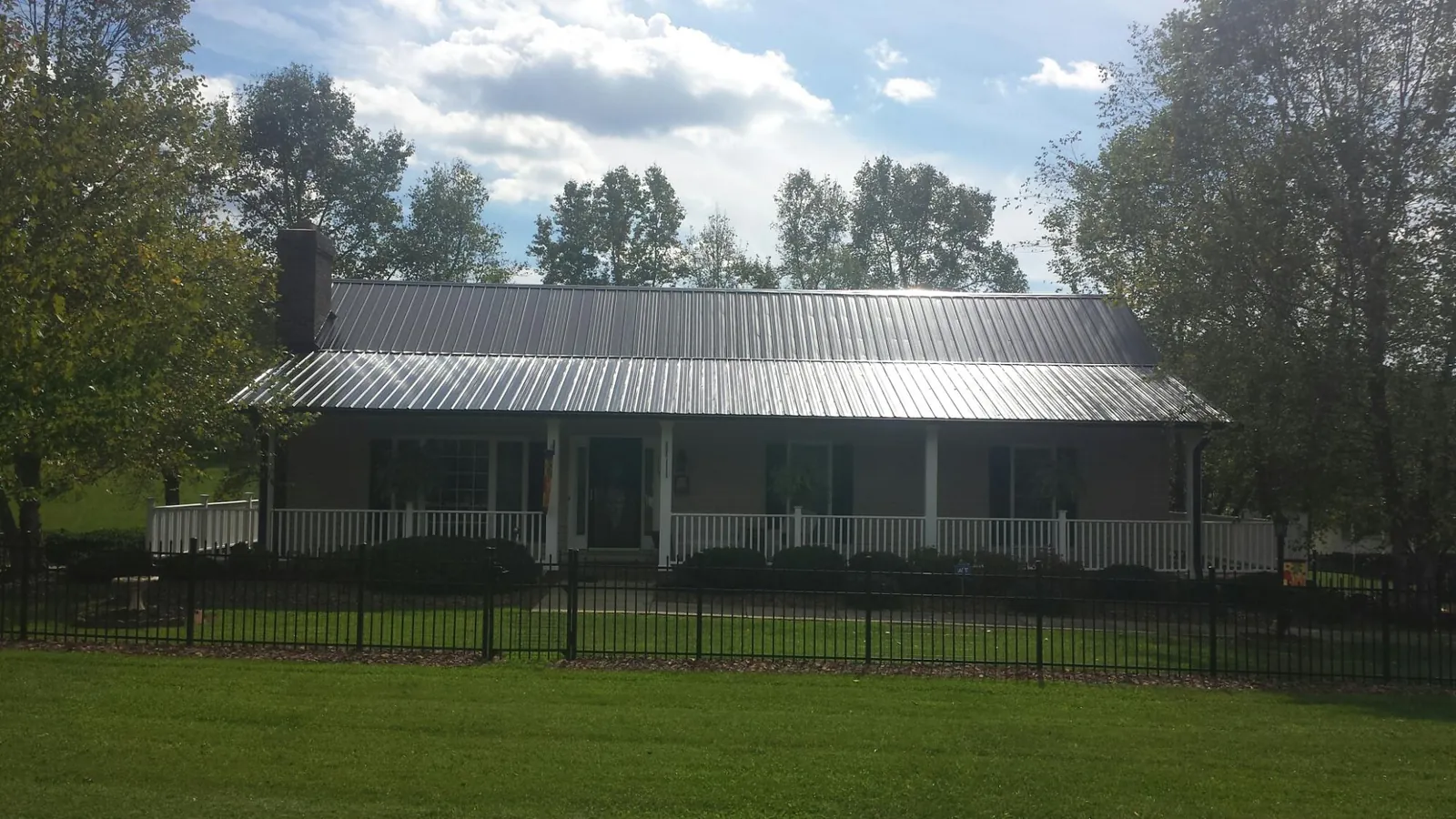 Gray metal roof on a brick ranch with a full width front porch — Gutter Guard Installation work by our crew in Windfall