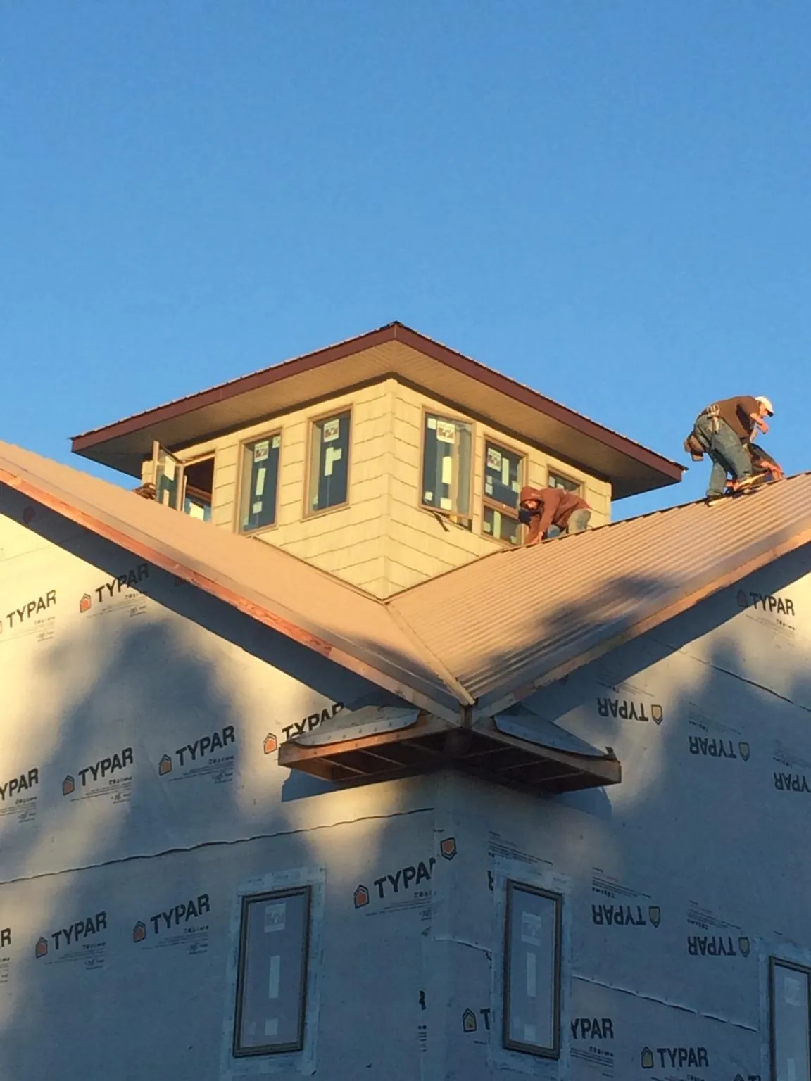 Roofers working around a rooftop cupola on a new metal roof at sunset — Roof Waterproofing in Windfall by Roofing Brothers